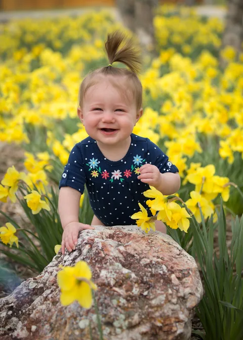 A smiling toddler among yellow daffodils